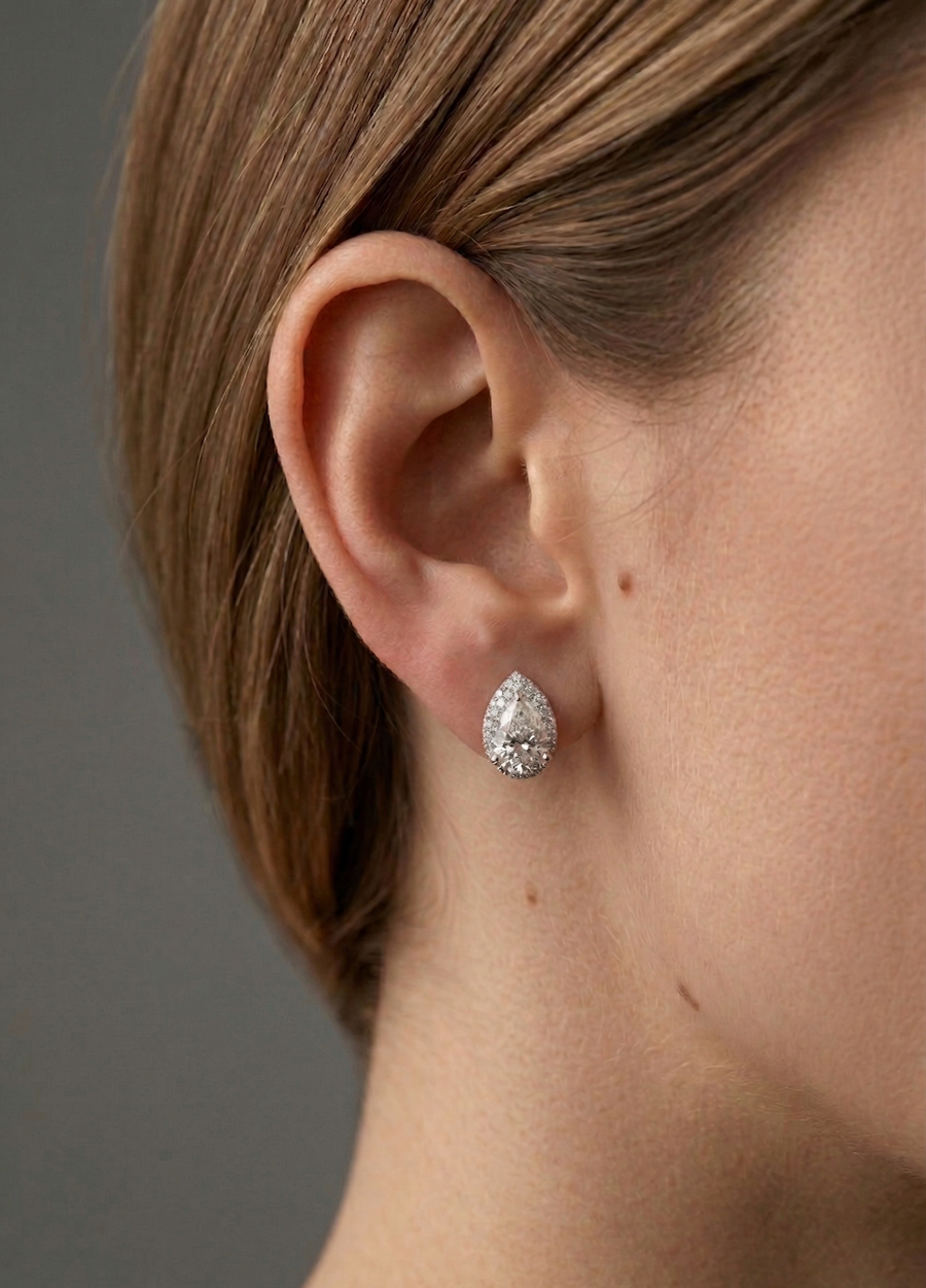 Close-up of an ear wearing a diamond earring with a neutral background