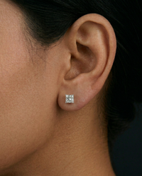 Close-up of an ear wearing a diamond stud earring with a dark background